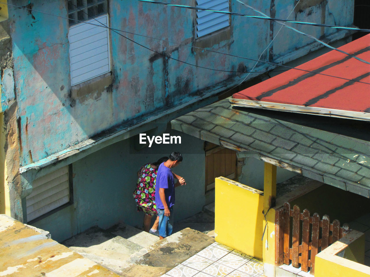 FULL LENGTH OF YOUNG WOMAN WALKING AGAINST BUILDING