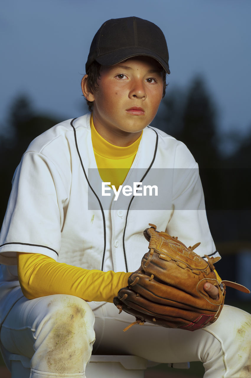 Portrait of a boy in white baseball uniform with his glove