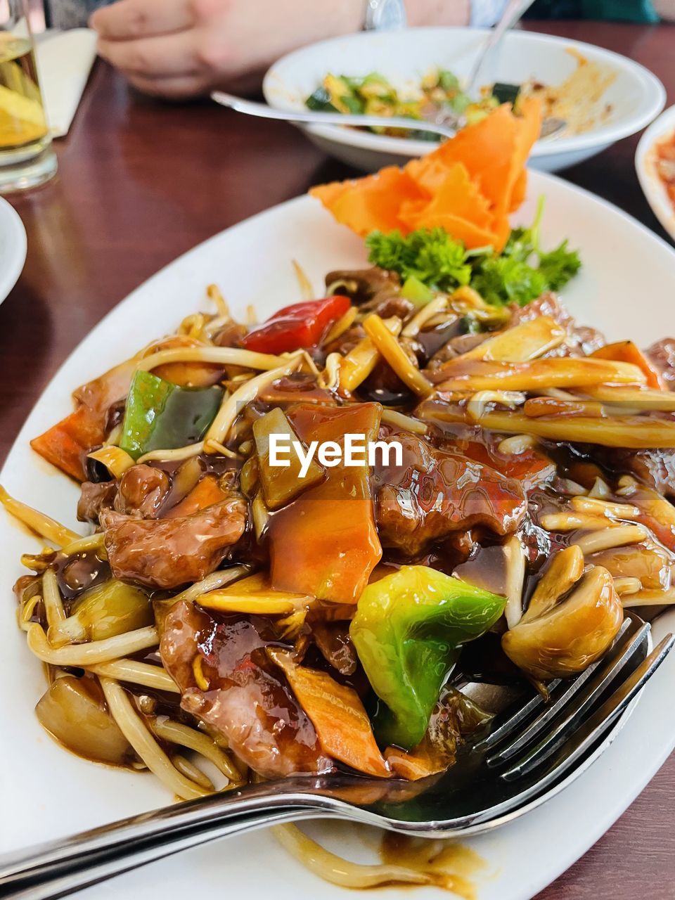 Close-up of chinese food in plate on table, beef with vegetables in a thick sauce