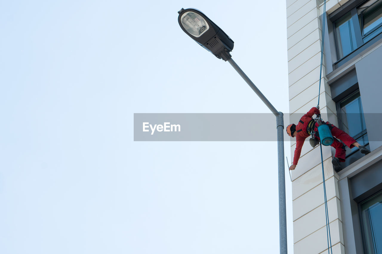 Low angle view of window washer on building