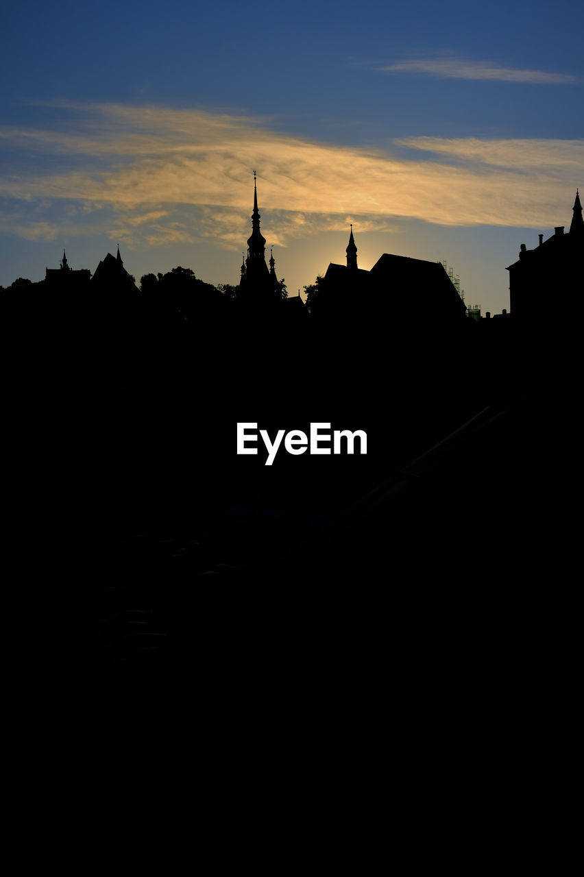 SILHOUETTE OF TEMPLE AGAINST BUILDINGS DURING SUNSET