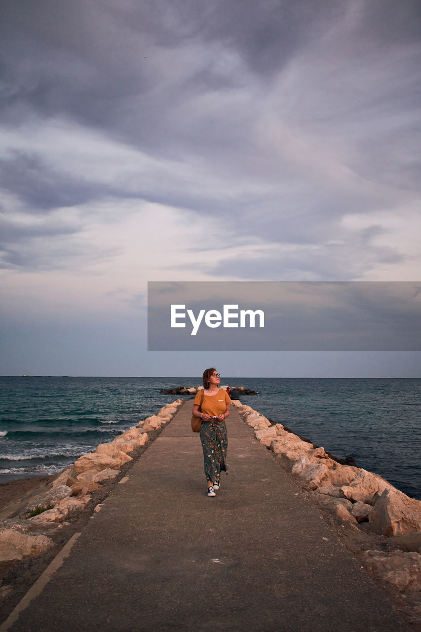 Middle-aged woman walks on a catwalk on the coast