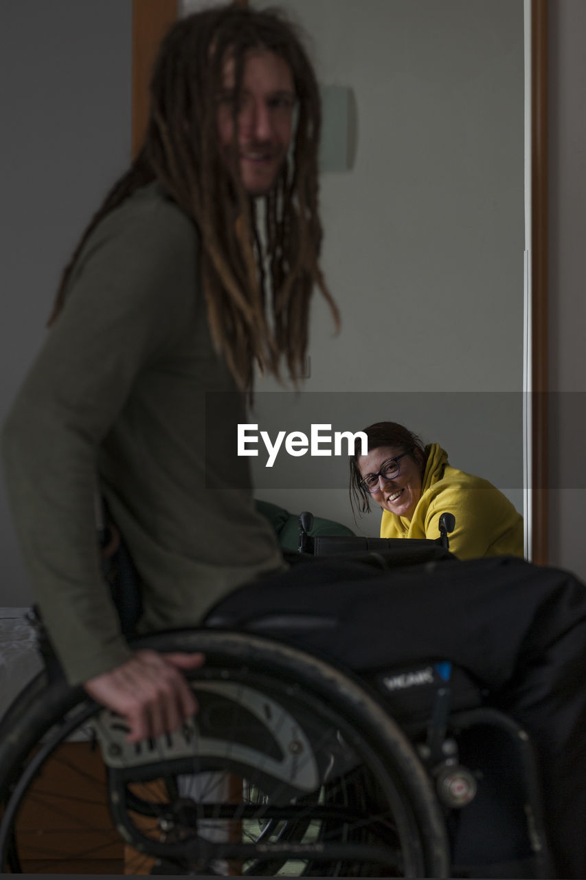 Man on wheelchair with smiling woman in background