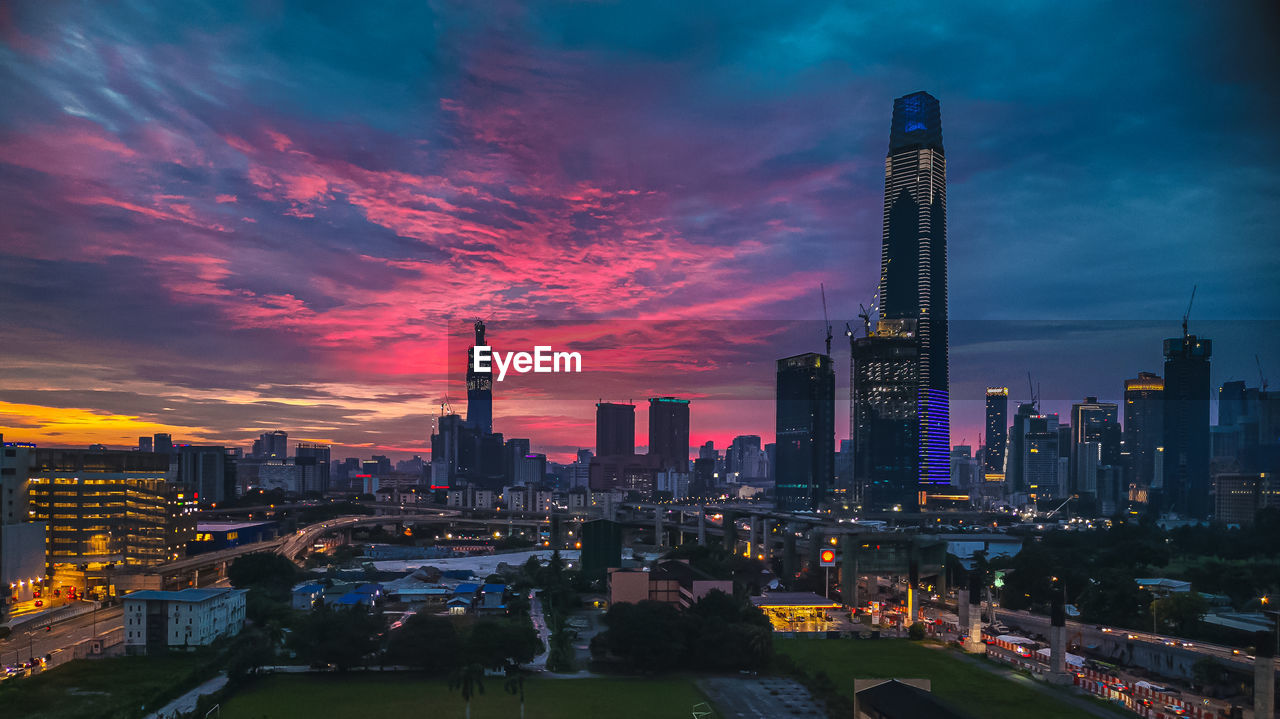 ILLUMINATED BUILDINGS IN CITY AGAINST SKY DURING SUNSET