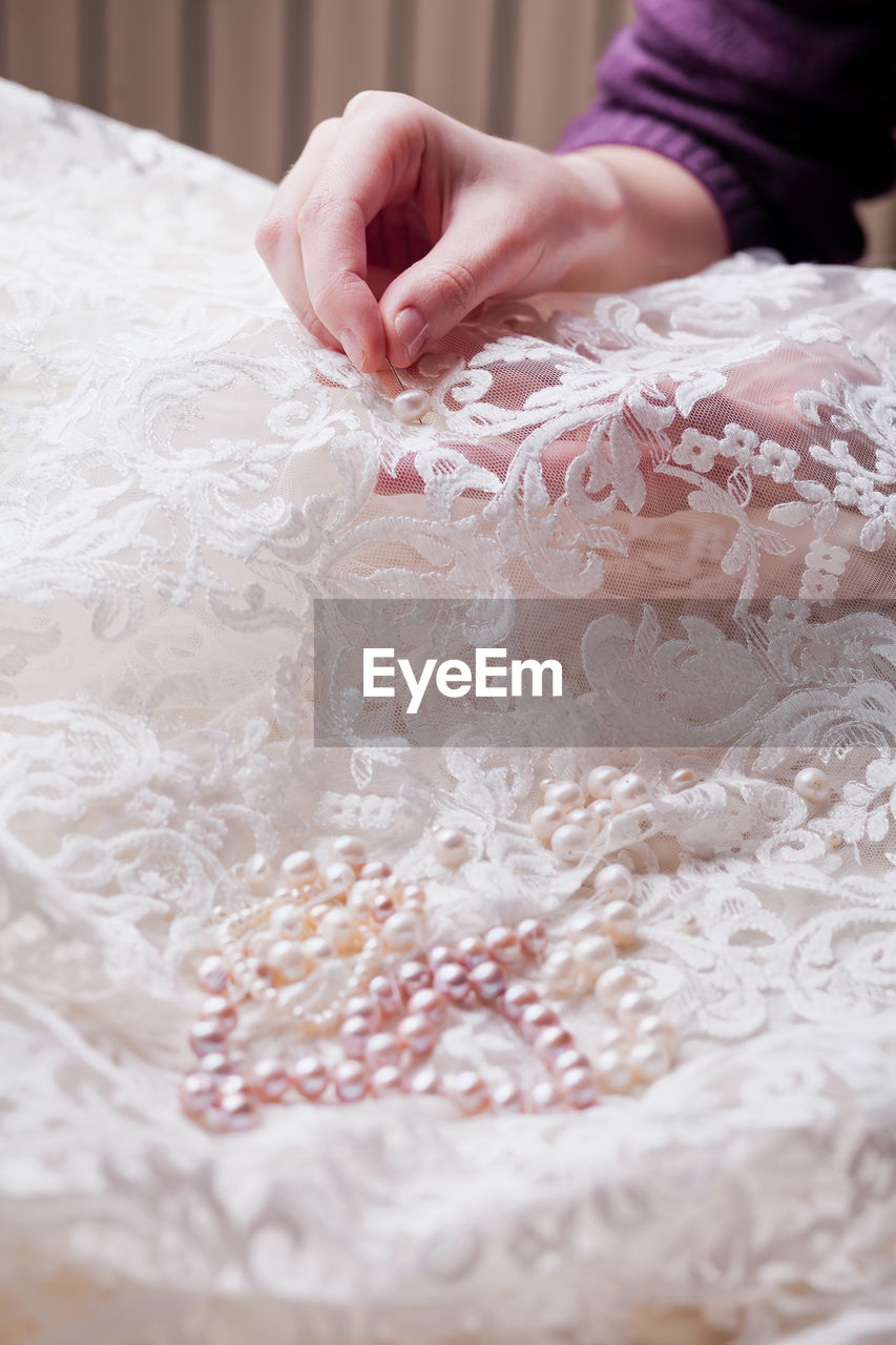 Cropped hands of woman stitching wedding dress