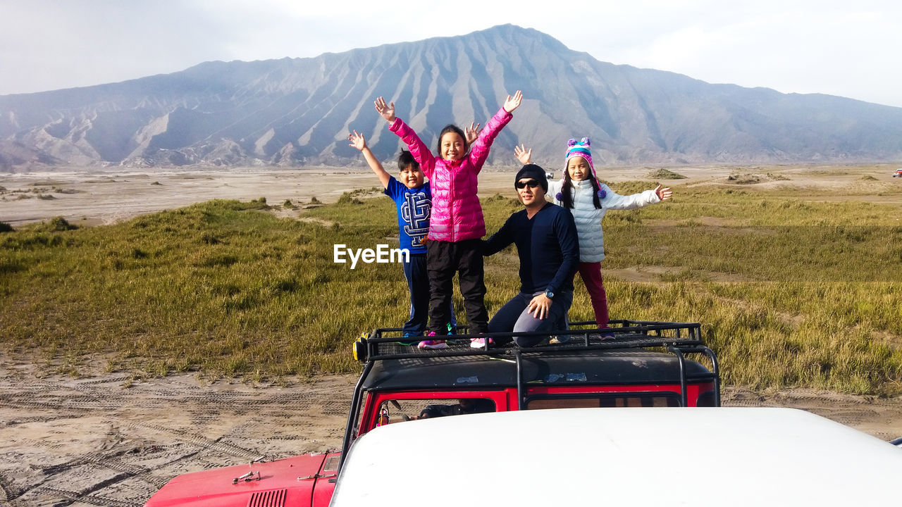 REAR VIEW OF WOMAN SITTING ON MOUNTAIN