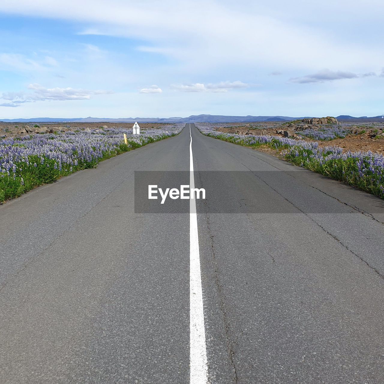 Road amidst field against sky