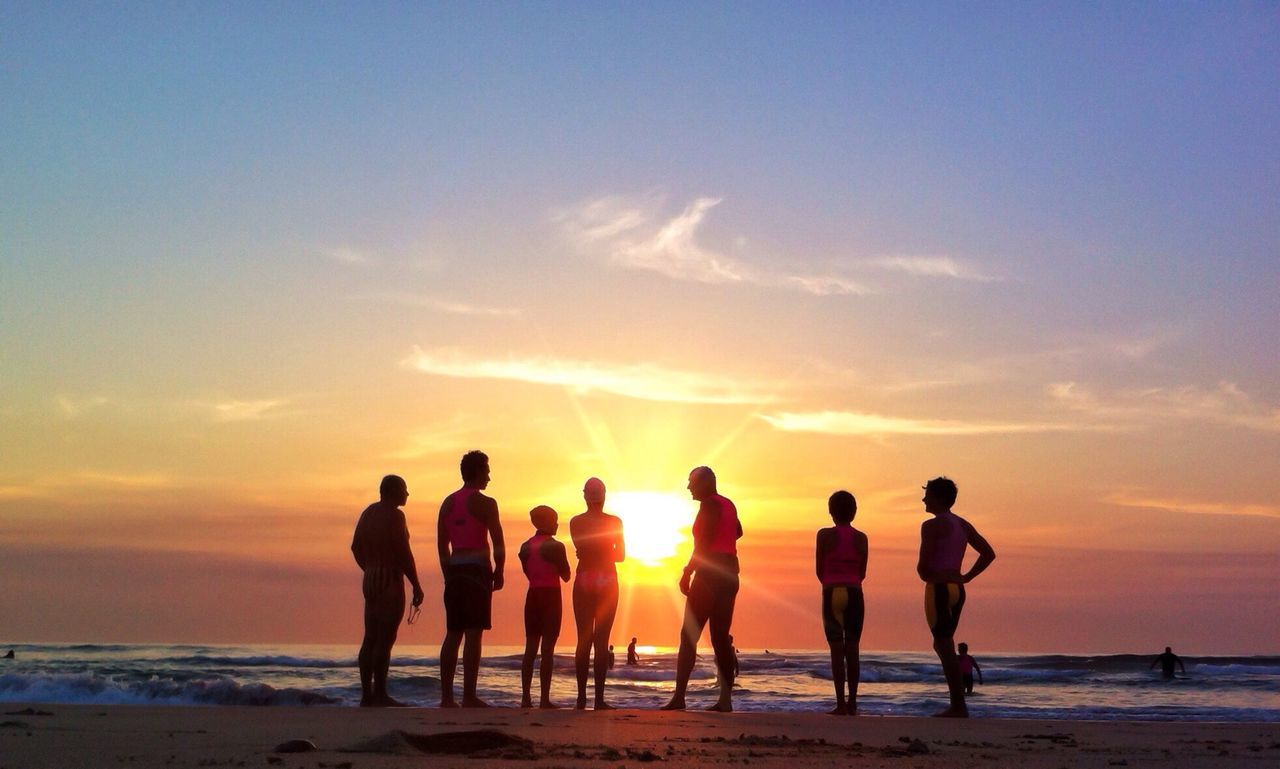 Full length of people standing at seashore on beach during sunset