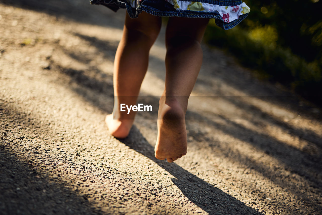 Low section of girl walking on road