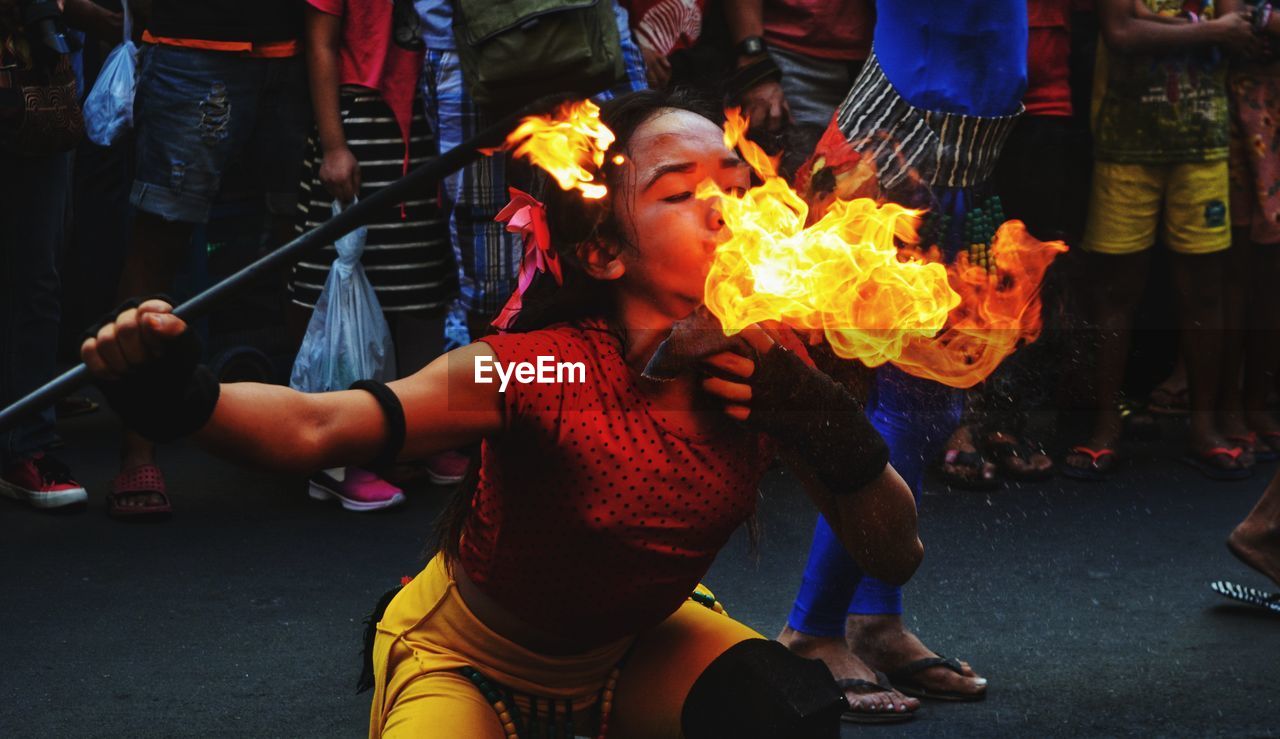 MAN HOLDING FIRE ON STREET AT NIGHT