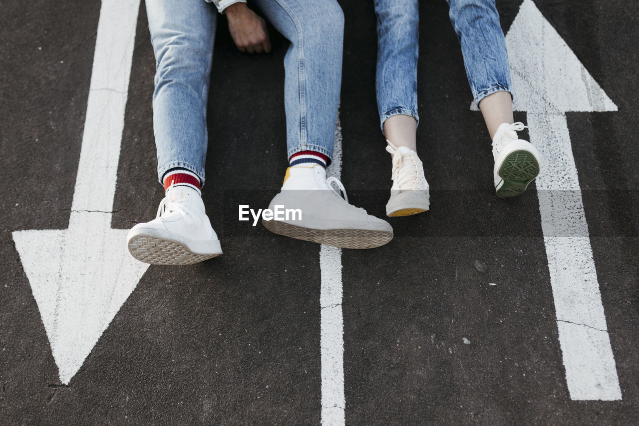 Unrecognizable young couple sitting between the signs on the floor of a skate park