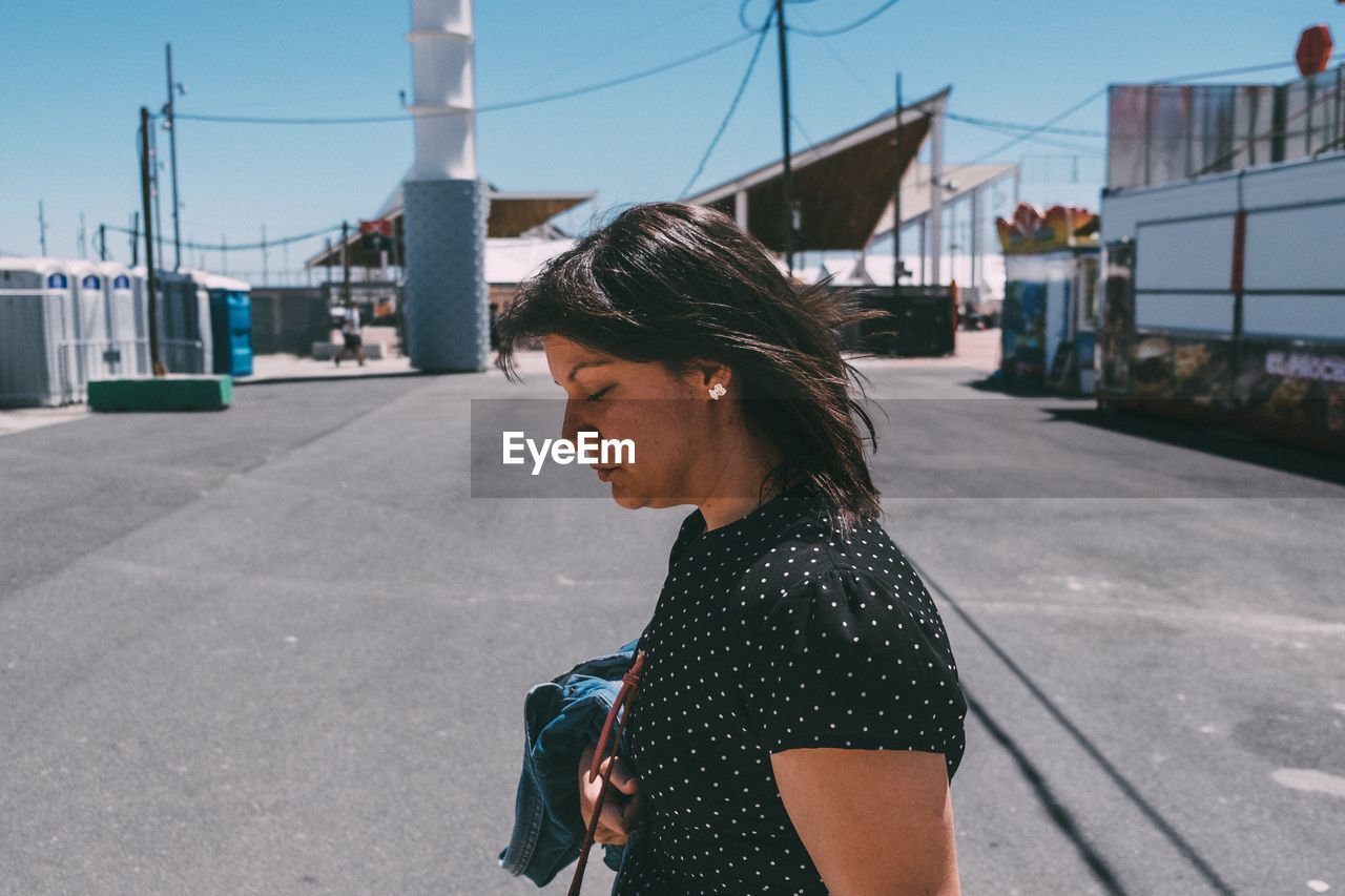 Side view of woman looking down while standing on street