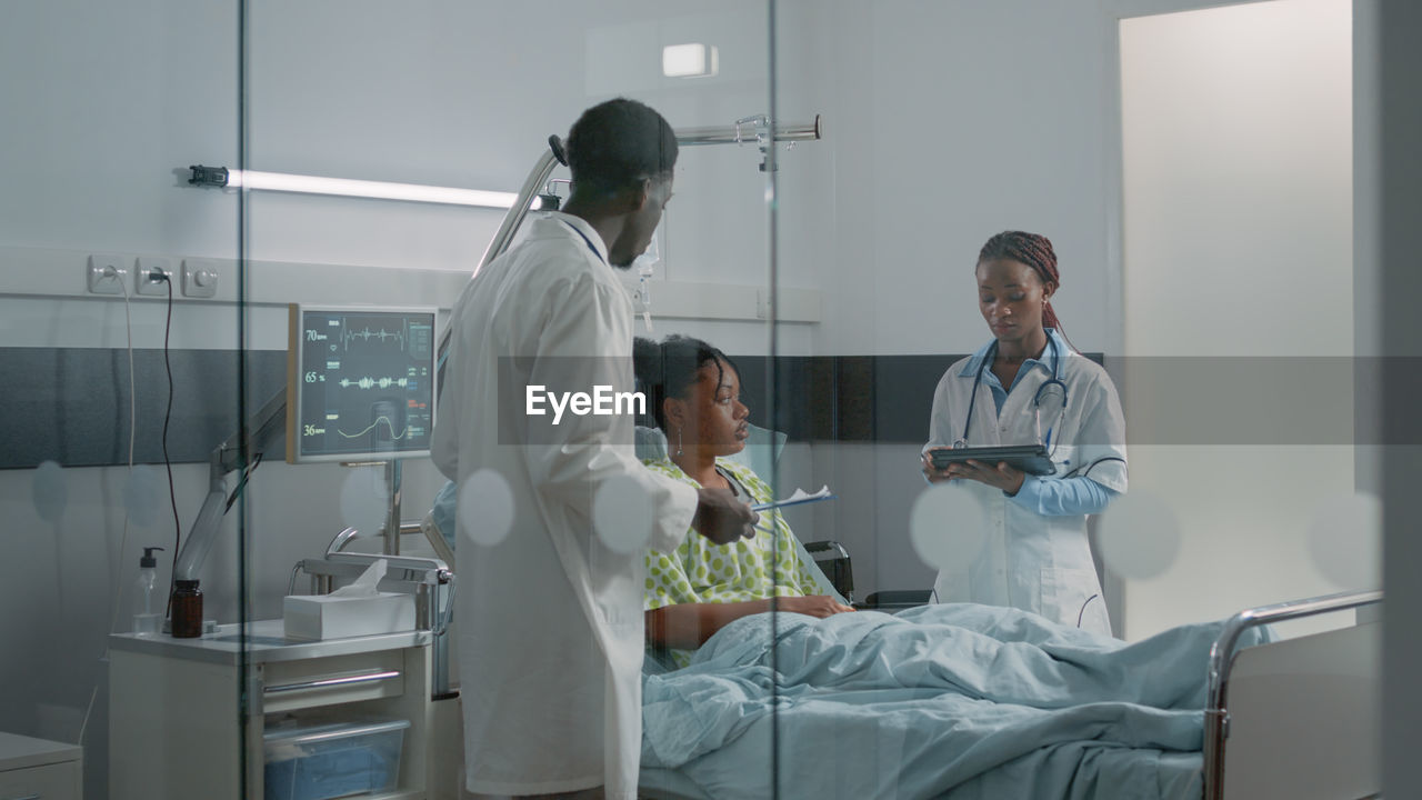 Doctor discussing with patient over tablet pc in hospital