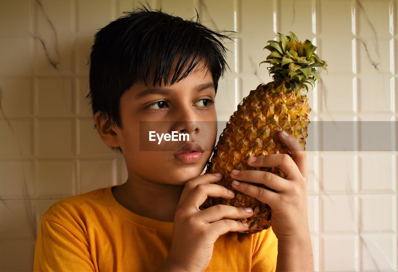 Portrait of boy holding pineapple