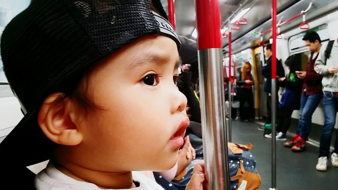 Close-up of innocent boy looking away while traveling in metro train