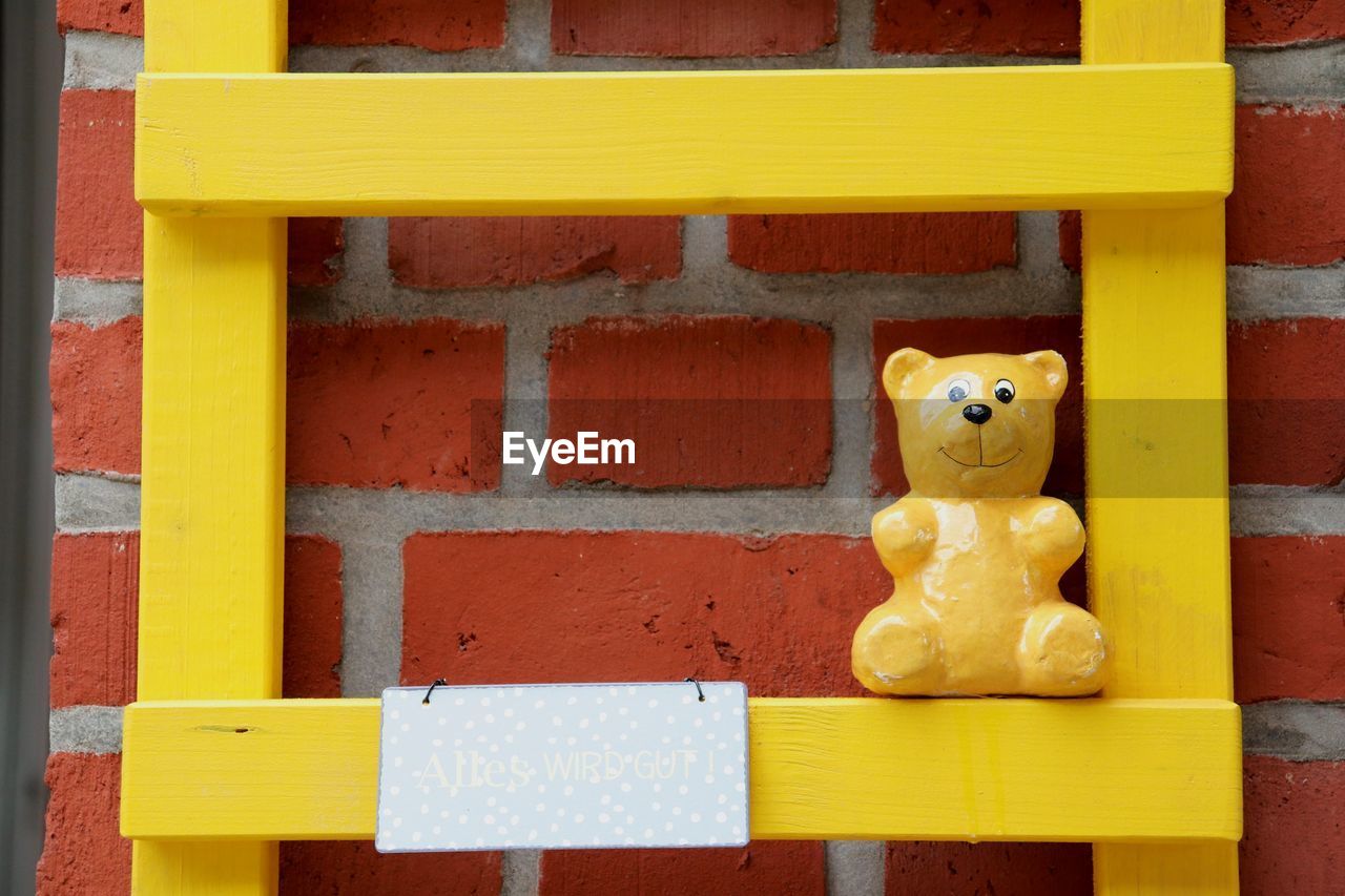 CLOSE-UP OF YELLOW TOY AGAINST WALL