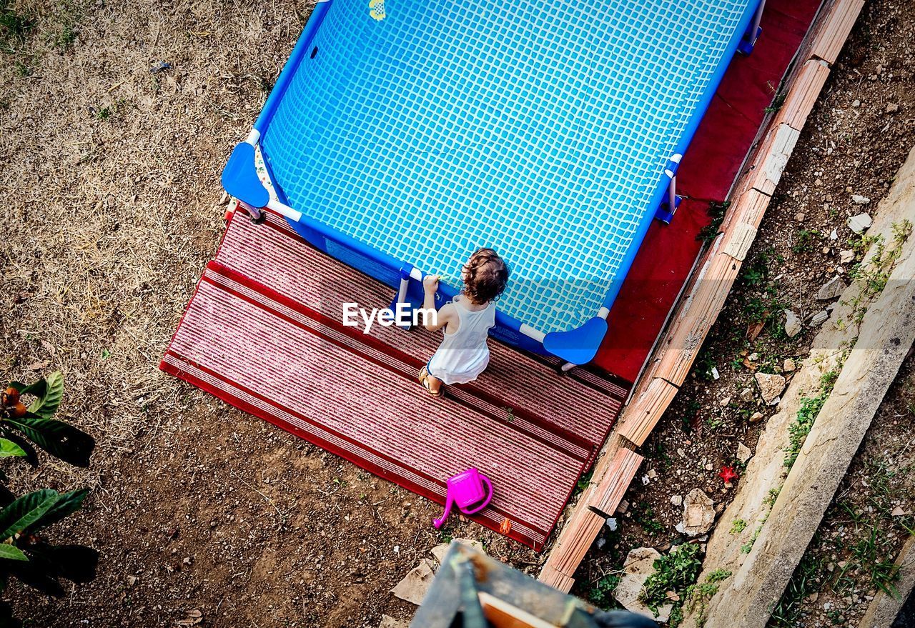 High angle view of baby playing with wading pool in yard