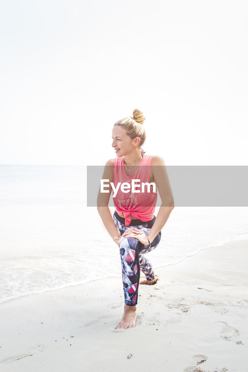 Full length of woman exercising on shore at beach