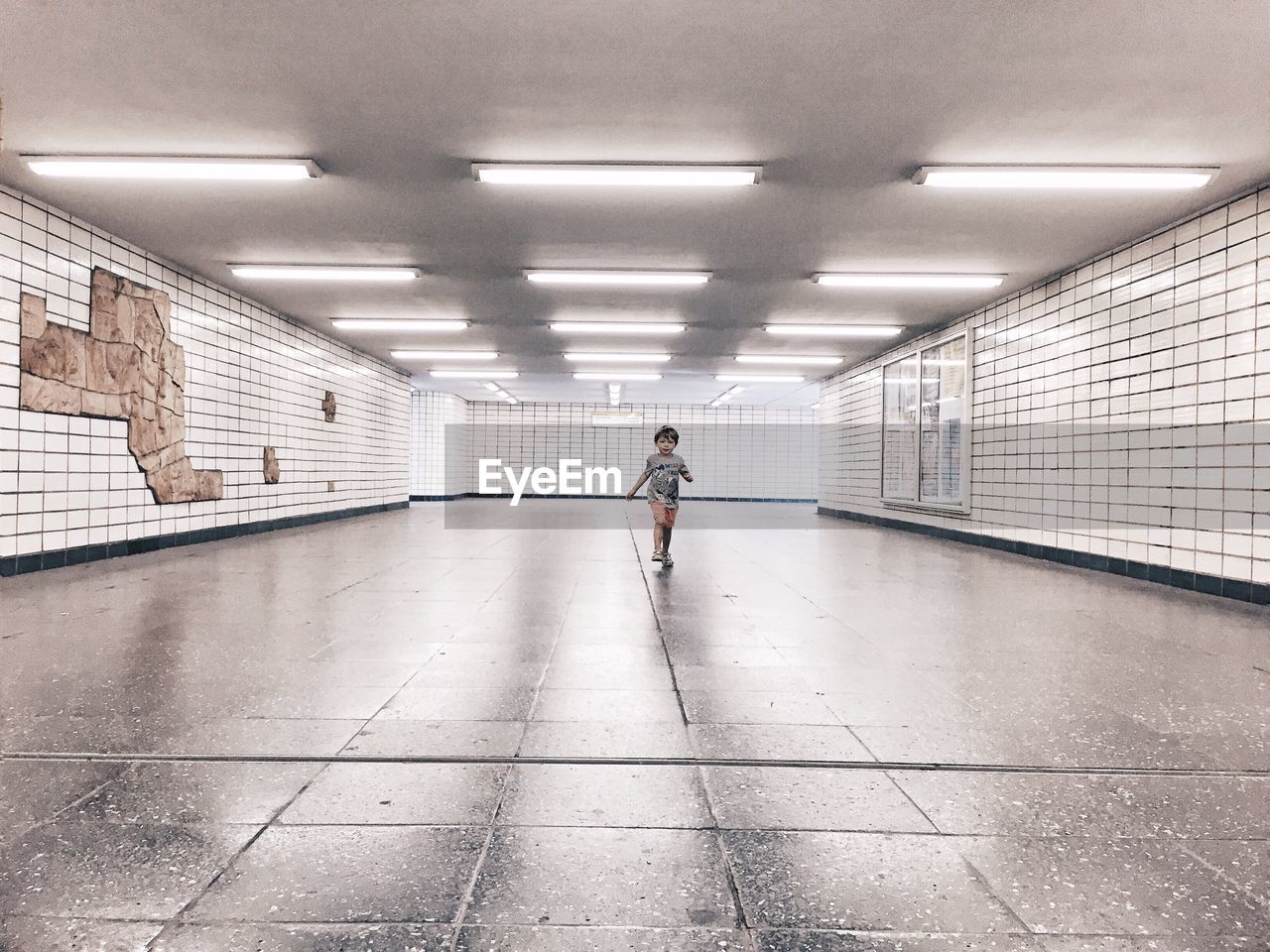 Full length of boy walking in illuminated subway