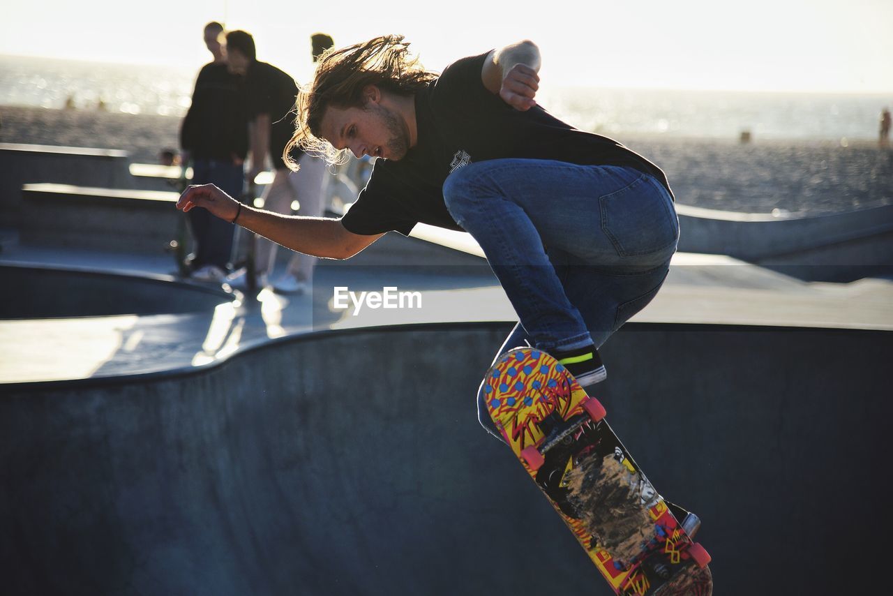 Full length of young man skateboarding at park against sky