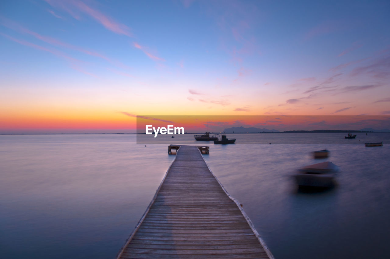 Pier over sea against sky during sunset