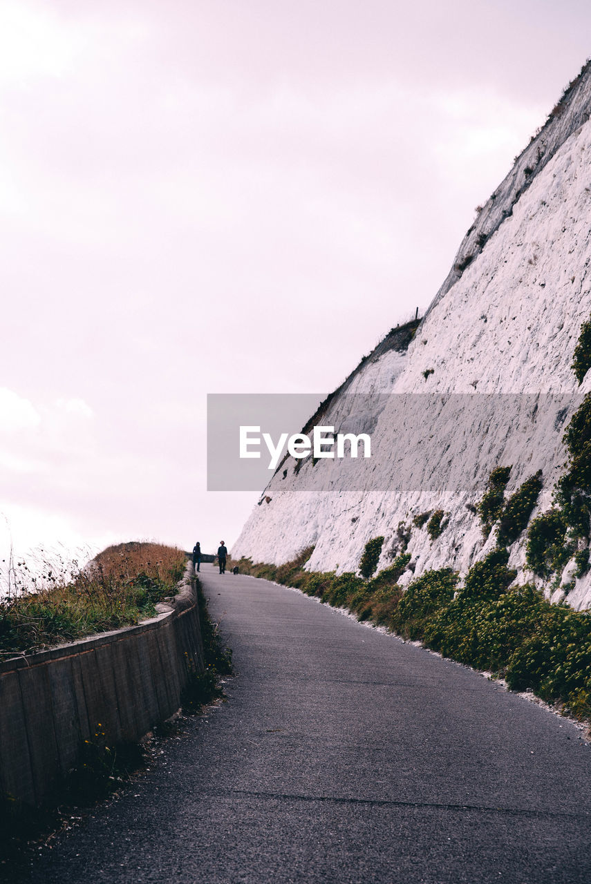 Road by cliff against sky