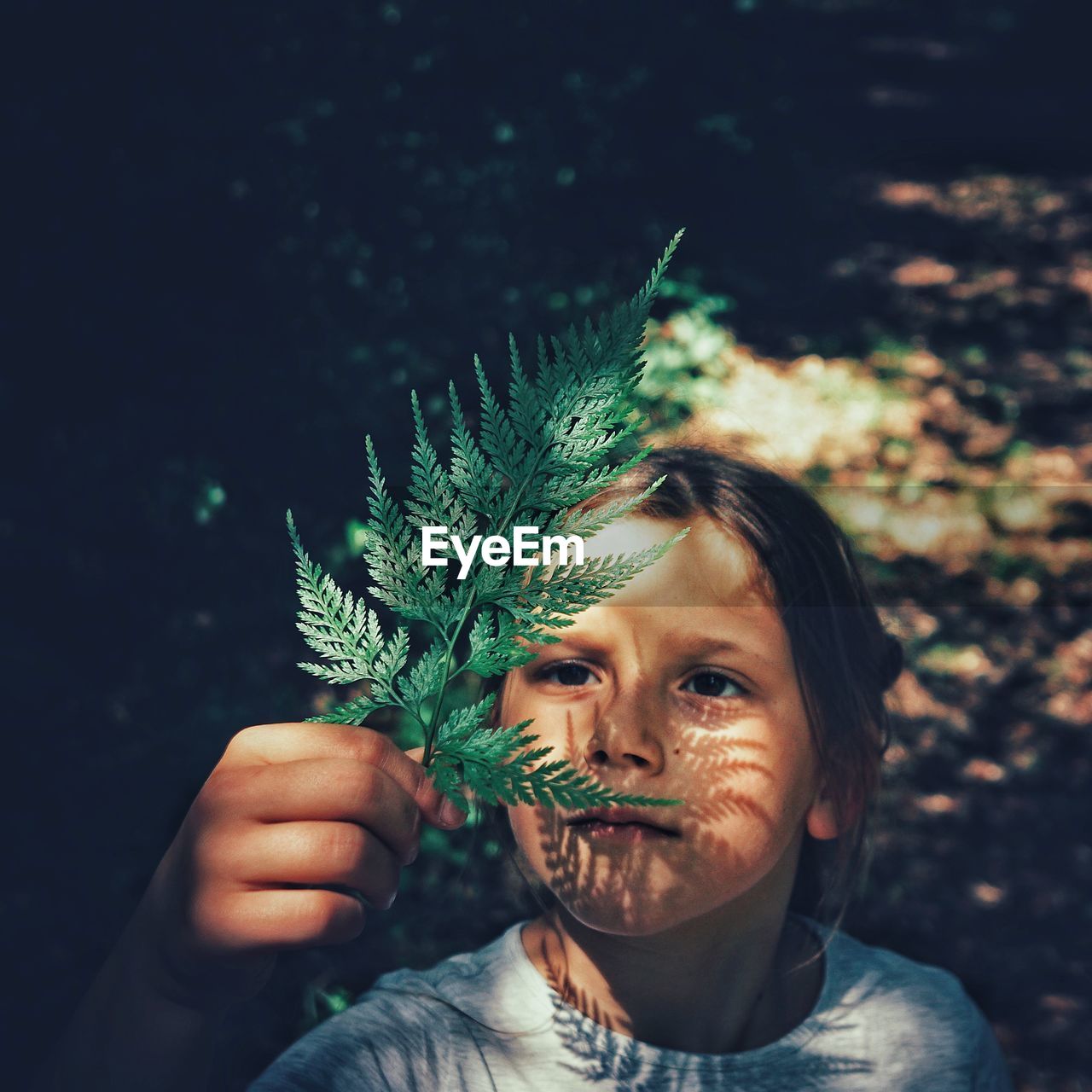 High angle view of girl holding leaf while standing outdoors