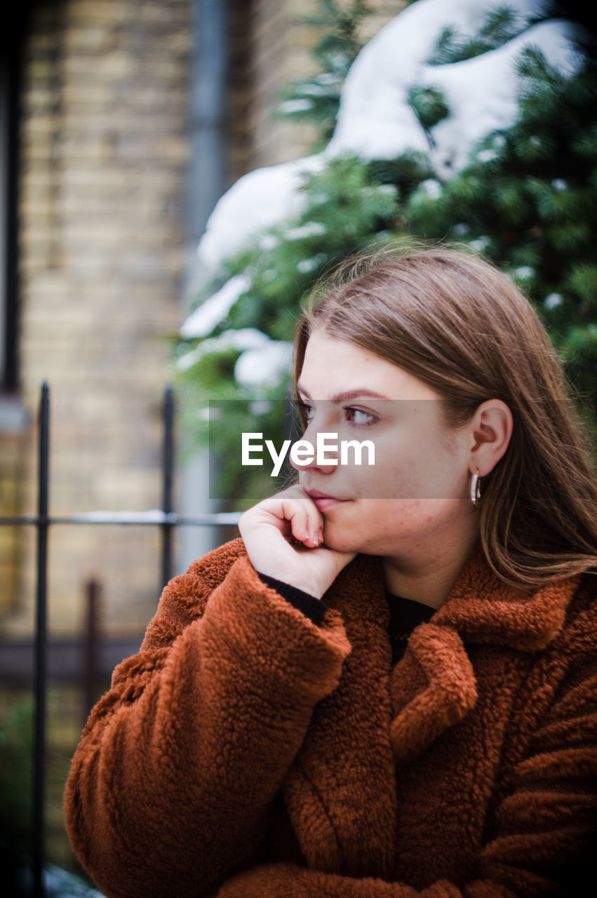 PORTRAIT OF YOUNG WOMAN LOOKING AWAY IN WINTER