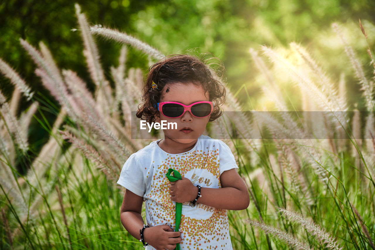 Portrait of girl wearing sunglasses standing on field