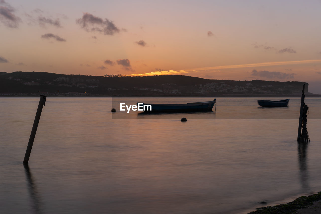 Fishing boats on a river sea at sunset in foz do arelho, portugal