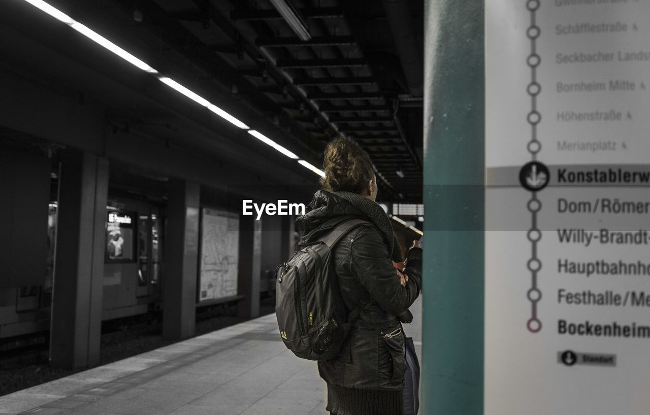 REAR VIEW OF MAN STANDING BY TEXT ON WALL