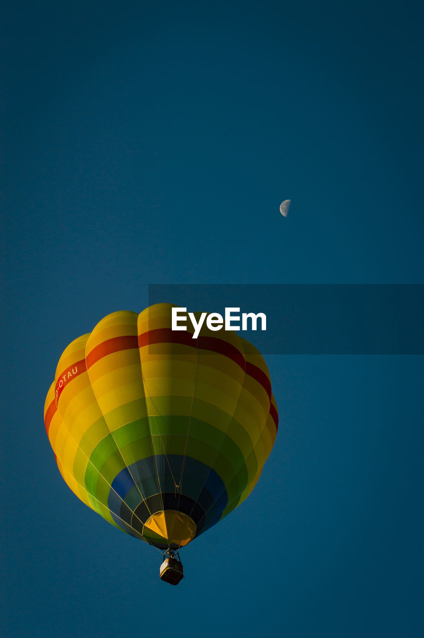 Low angle view of hot air balloon against blue sky and moon