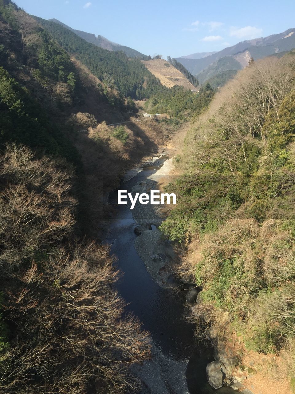 High angle view of stream amidst mountains at forest