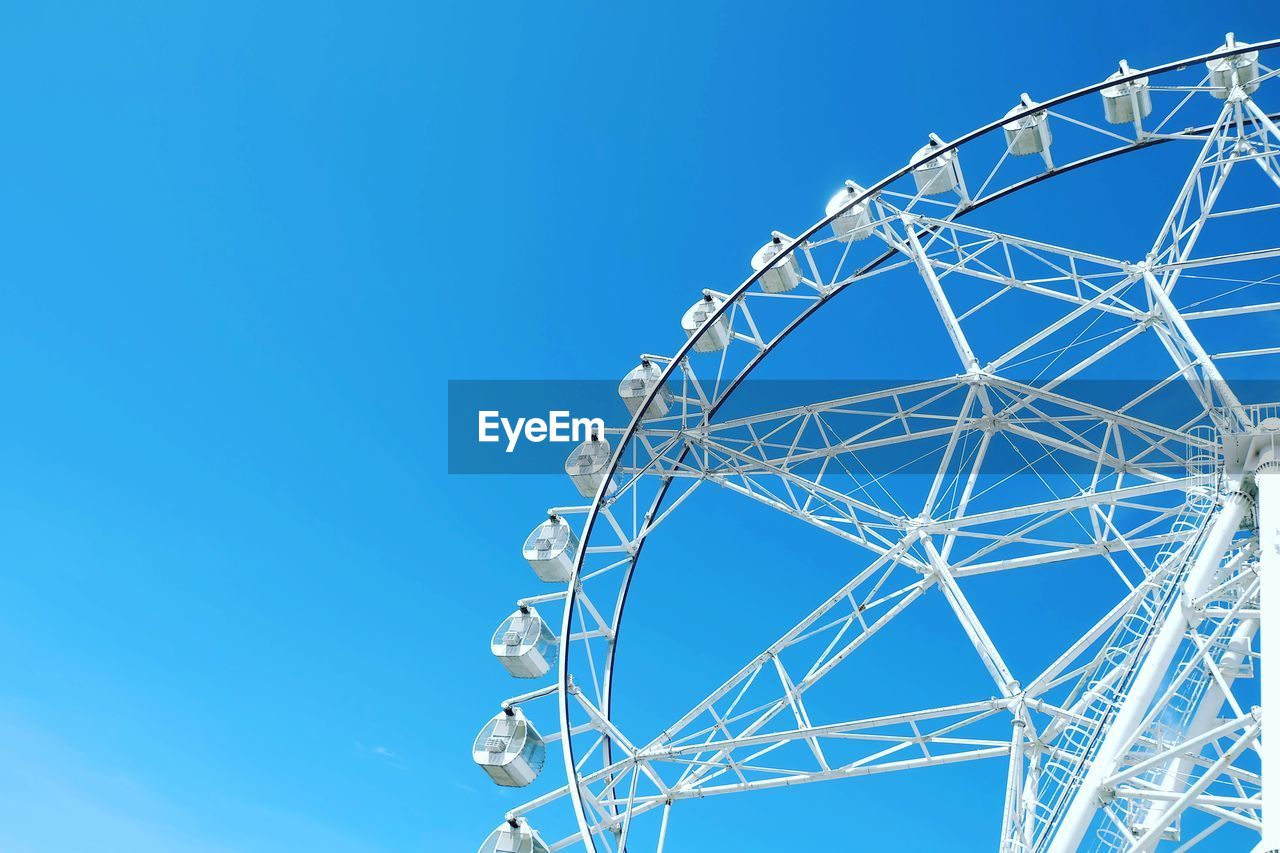 Low angle view of ferris wheel against clear blue sky