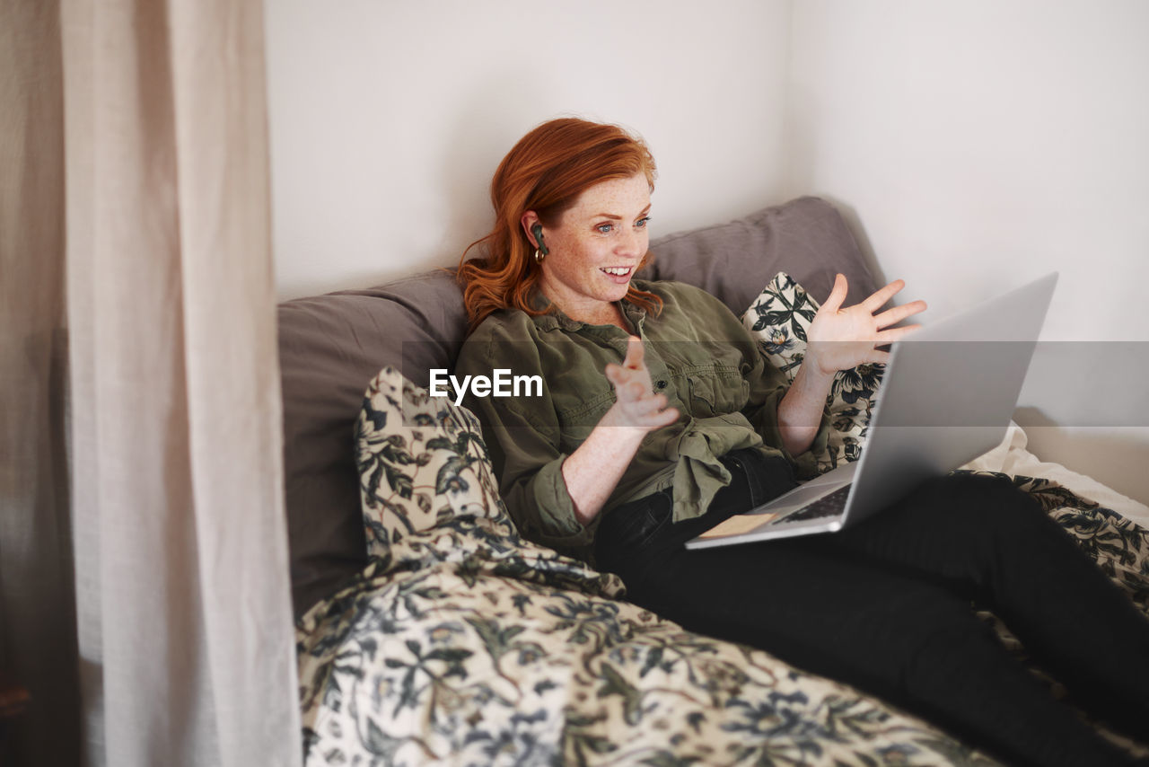 Smiling woman using laptop on bed