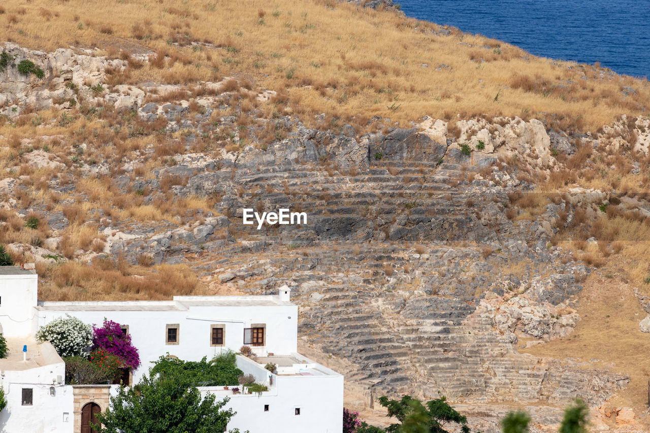 Excavation of ancient amphitheater in lindos on greek island rhodes with white house in foreground