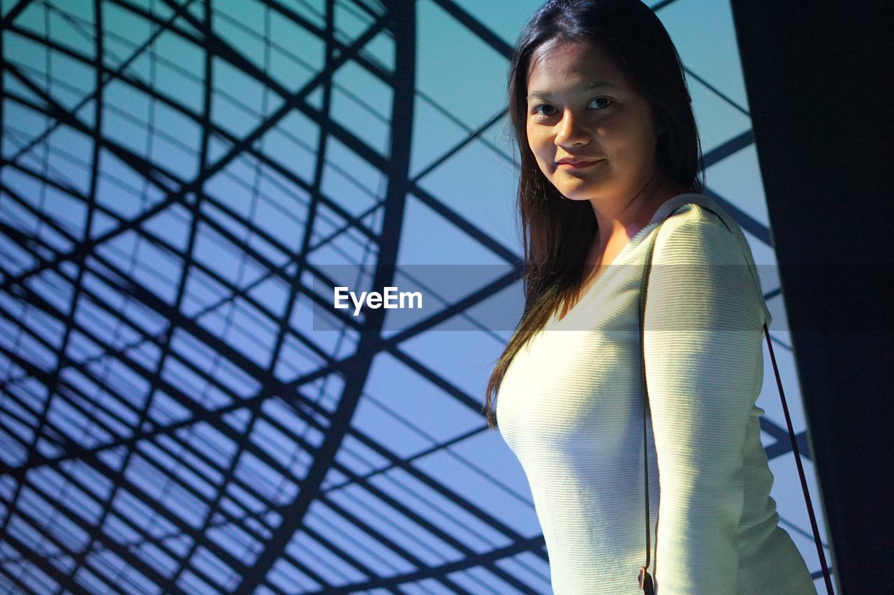 Portrait of smiling mid adult woman standing glass ceiling