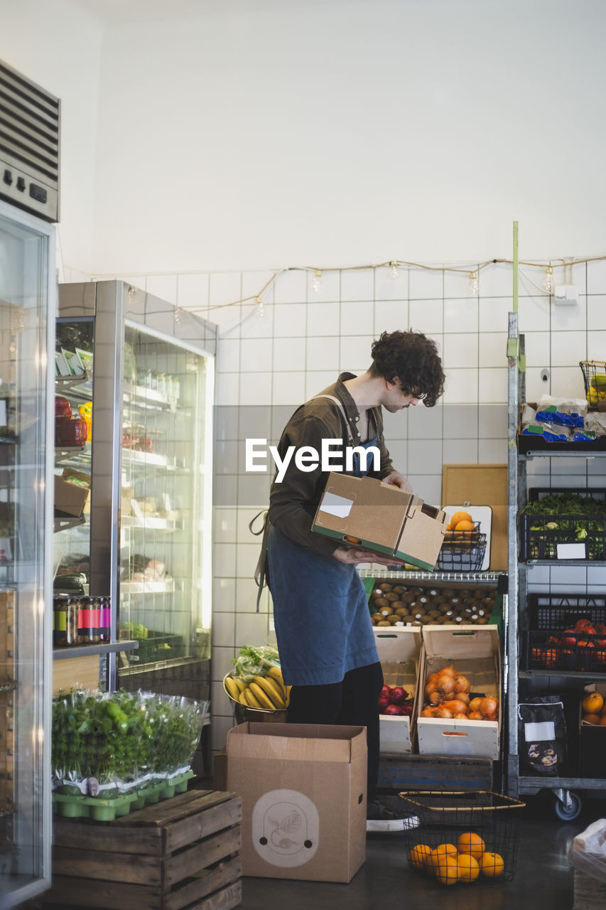 Male owner with fruit box standing in store