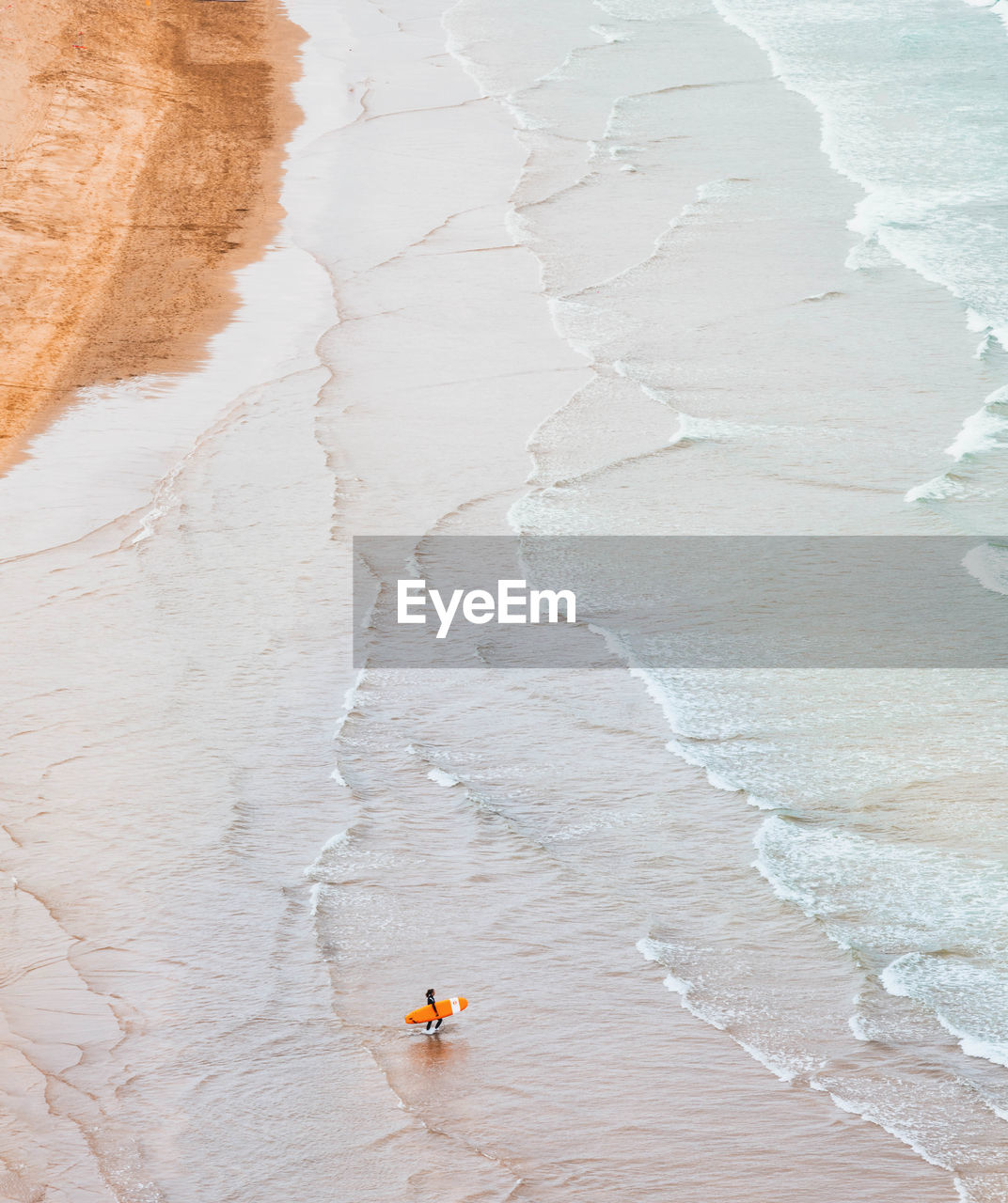 Aerial view of mature man with surfboard at beach