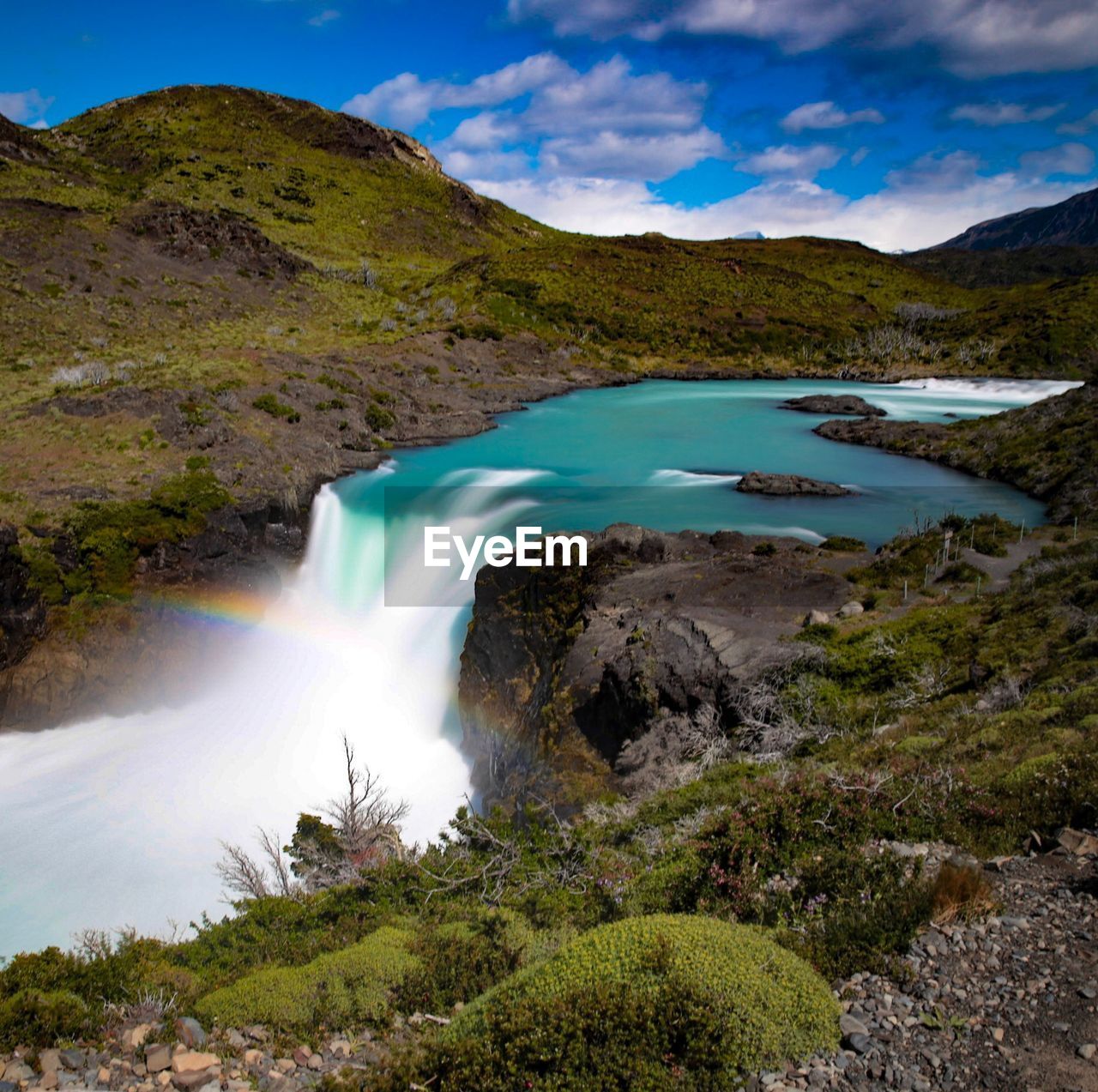 SCENIC VIEW OF WATERFALL BY MOUNTAIN AGAINST SKY