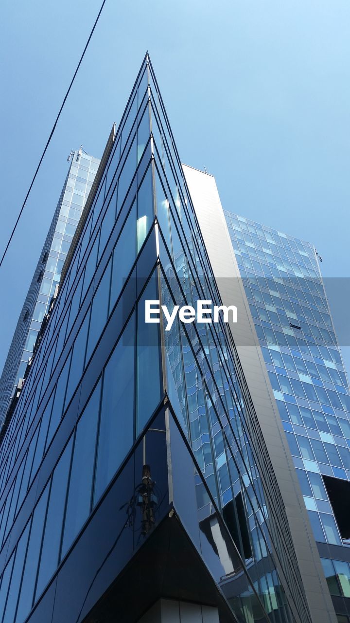 LOW ANGLE VIEW OF MODERN SKYSCRAPER AGAINST BLUE SKY