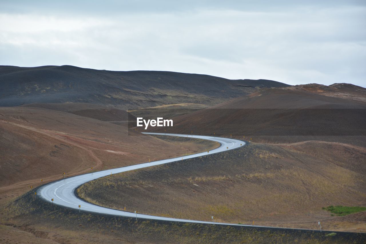 Scenic view of road by mountains against sky