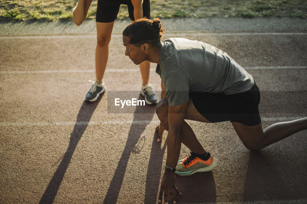 High angle view of focused man kneeling on running track