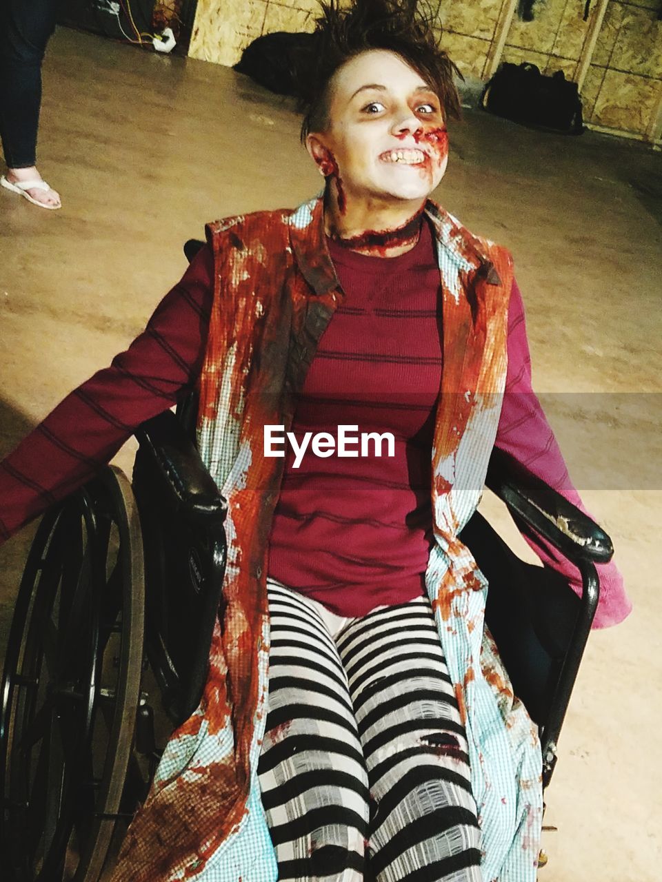 Portrait of young woman sitting on wheelchair with halloween make-up