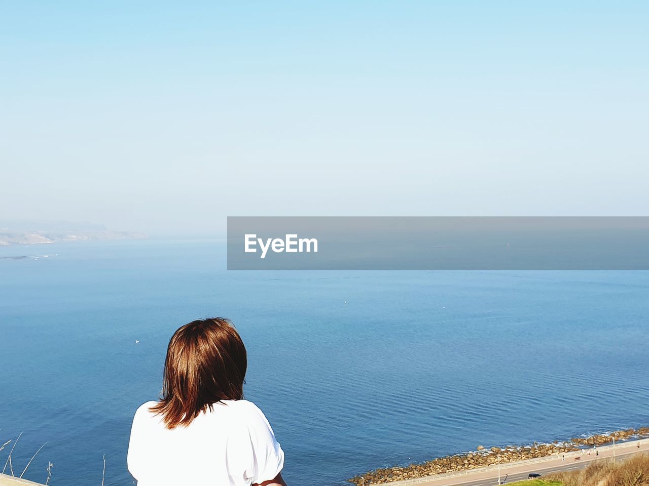 REAR VIEW OF WOMAN OVERLOOKING SEA