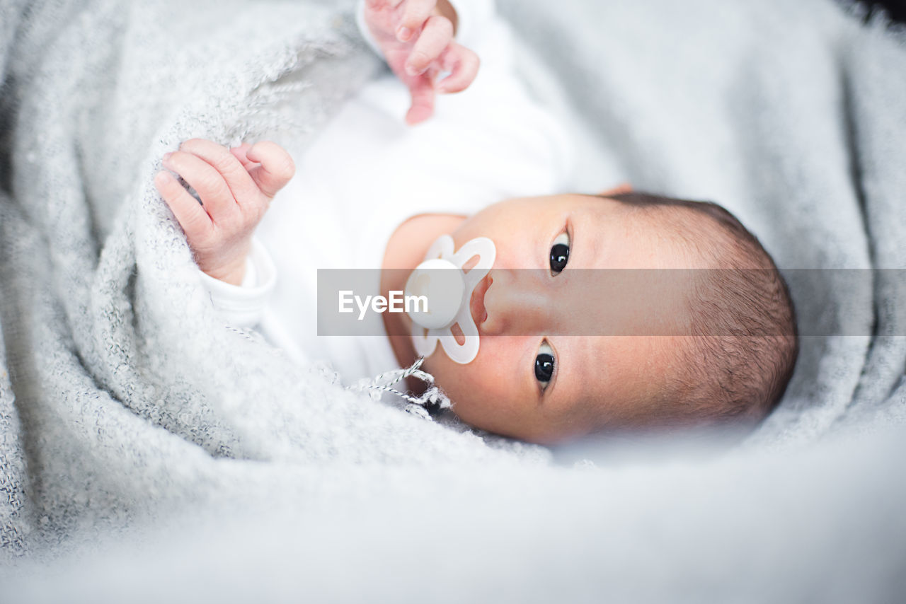 Close-up portrait of cute baby boy lying on bed