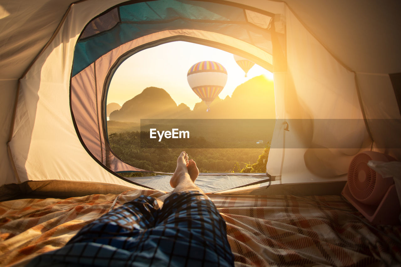 Low section of man relaxing in tent during sunny day