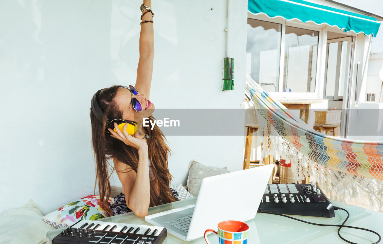 Happy woman enjoying music while standing against white wall