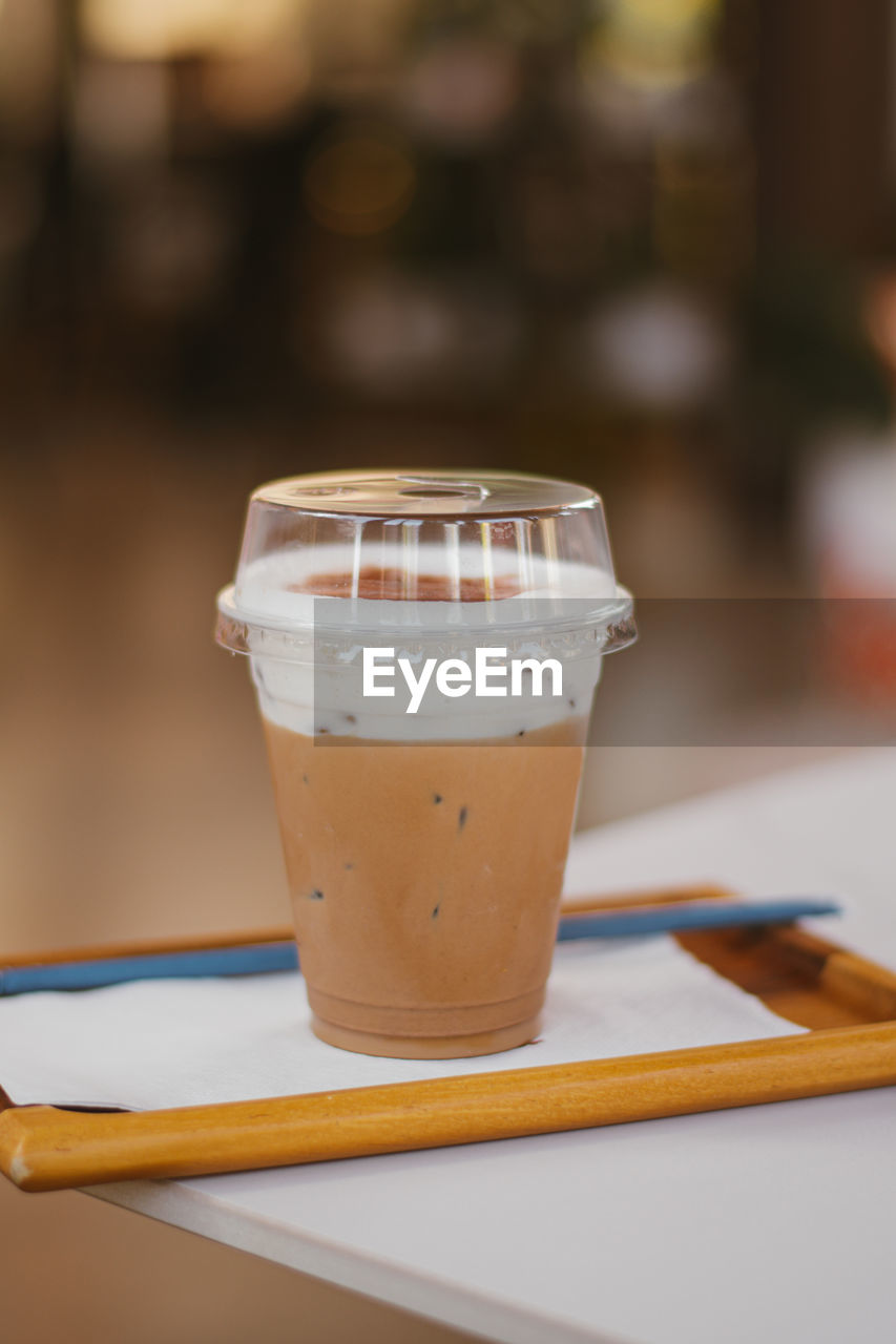 Iced cappuccino in a plastic mug on white table in coffee shop.