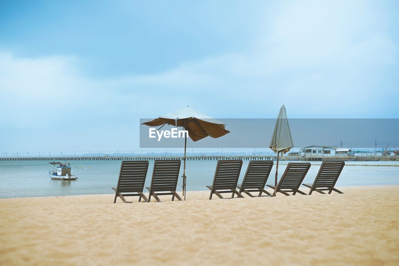 Chairs on beach against sky